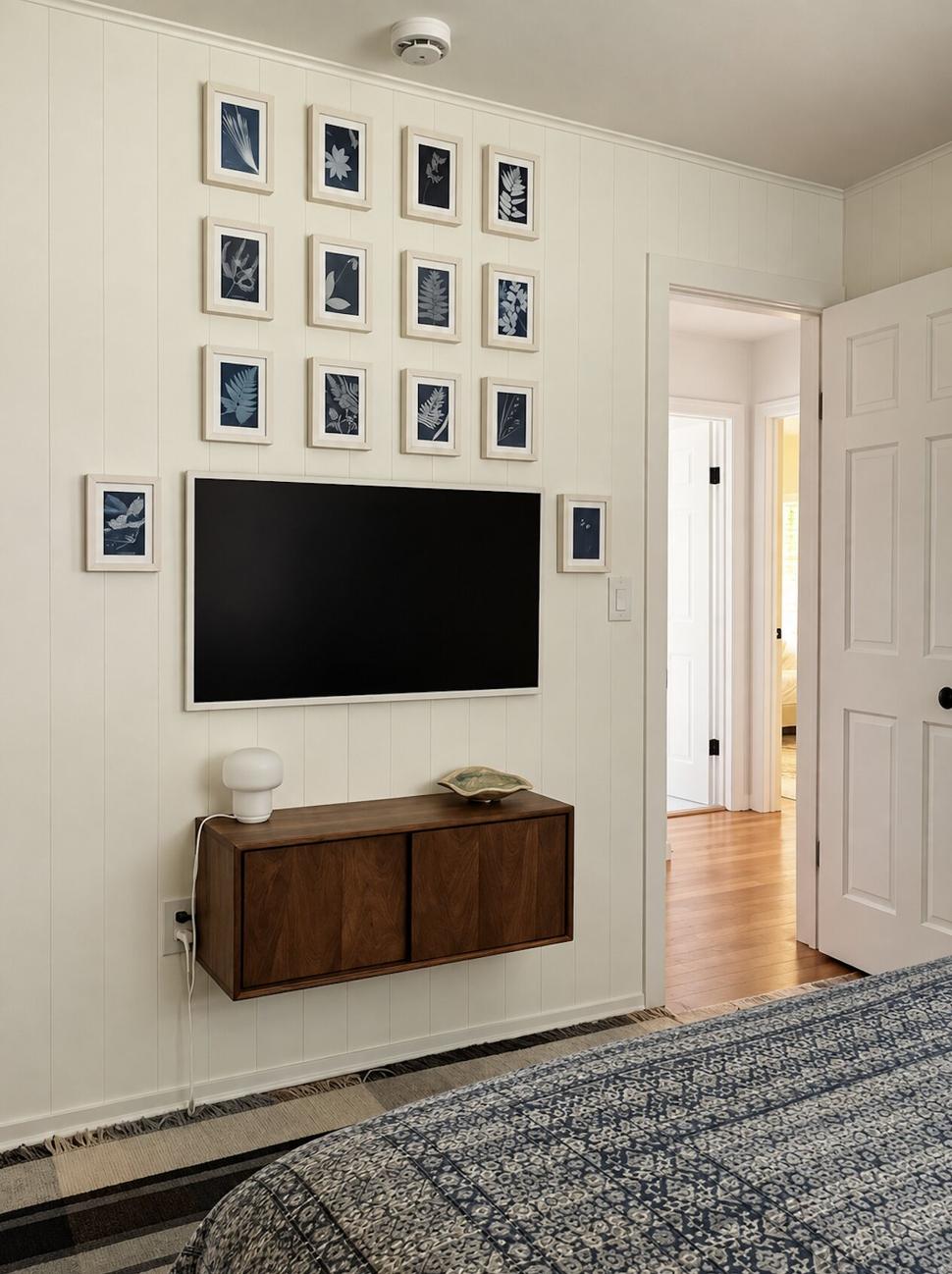 Ranch & Barn — bedroom wall hung with a grid of framed cyanotype botanicals above a floating walnut cabinet